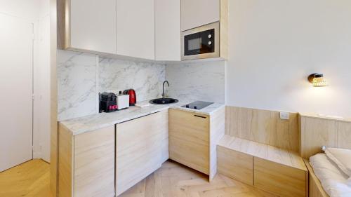 - une cuisine avec des murs blancs et des placards en bois dans l'établissement Bluestay 534 - Superbe appartement à Paris, à Paris