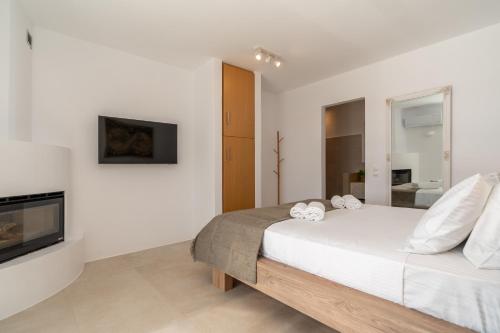 a white bedroom with a bed and a fireplace at Gaia & Thalassa Villa Orionas in Otziás