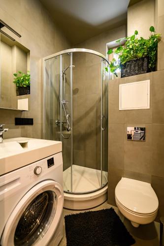 a bathroom with a shower and a washing machine at Liepaja Apartments Parkside in Liepāja