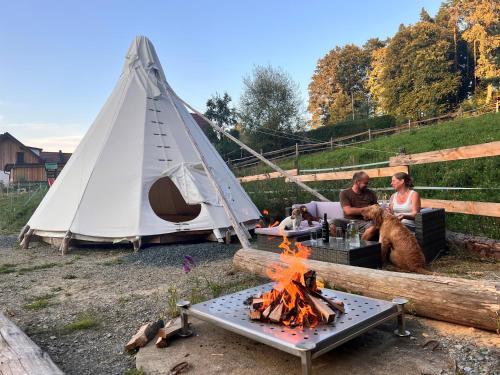 a group of people sitting around a fire in front of a tent at Tipi-Glamping am Gut Kunterbunt in Kaindorf