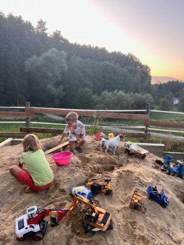two children playing in a sandbox with toys in the sand at Tipi-Glamping am Gut Kunterbunt in Kaindorf