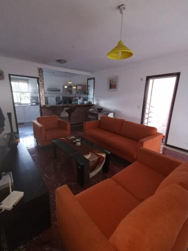 a living room with orange couches and a table at Very Calm, low cost in Triolet