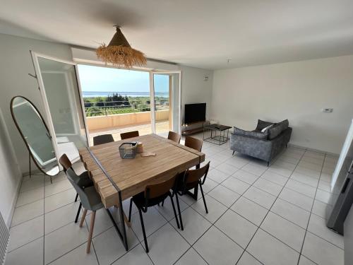 une salle à manger avec une table, des chaises et un canapé dans l'établissement Cocon d'Ingril Penthouse vue mer, à Frontignan