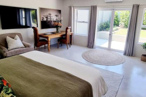Un dormitorio con una cama y una mesa y sillas. en C'est la Vie 1, en Franschhoek