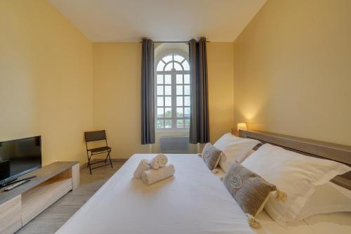 una camera da letto con un grande letto bianco e una televisione di Le Richelieu - Magnifique duplex avec une vue Incroyable a Bordeaux