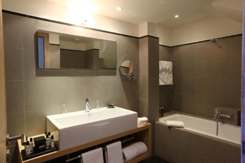 a bathroom with a white sink and a bath tub at Le Pinarello in Sainte-Lucie de Porto-Vecchio