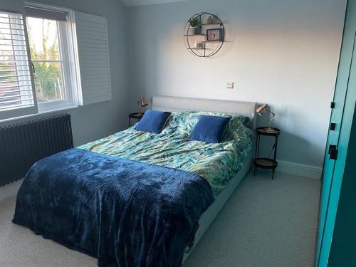 a bedroom with a bed with a blue comforter and pillows at Beautiful family home with hot tub in Wivenhoe