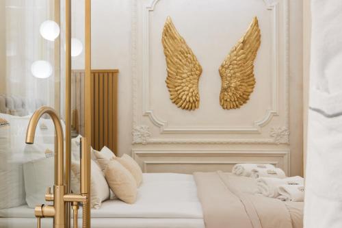 two gold wings on a wall above a bed at Jacuzzi Mirror Suite by Downtown Apartments in Gdańsk