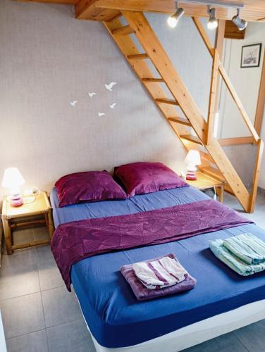 - une chambre dotée d'un lit avec des draps violets et des escaliers dans l'établissement Grand appartement proche port et plages, 6 à 8 pers, 3 chambres, climatisé, au Cap d'Agde