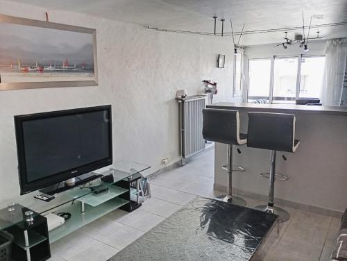 - un salon avec une télévision à écran plat et deux chaises dans l'établissement Grand appartement proche port et plages, 6 à 8 pers, 3 chambres, climatisé, au Cap d'Agde
