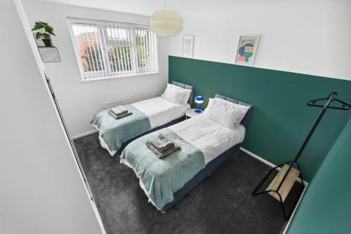a bedroom with two beds and a mirror at Stylish Home From Home 3 bed house, sleeps 6, private parking, WiFi Leamington Spa in Leamington Spa