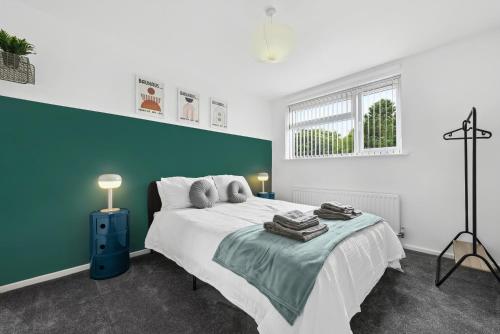 a bedroom with a large bed with a blue accent wall at Stylish Home From Home 3 bed house, sleeps 6, private parking, WiFi Leamington Spa in Leamington Spa