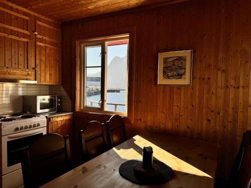a kitchen with a table and a stove and a window at Toppøy Rorbuer in Reine