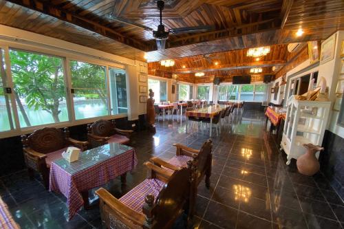 un ristorante vuoto con tavoli, sedie e finestre di Baan Sanuan Resort a Ban Sawai Chik Noi
