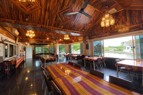 a restaurant with wooden ceilings and tables and chairs at Baan Sanuan Resort in Ban Sawai Chik Noi