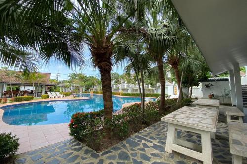 a swimming pool with a palm tree and a bench at Baan Sanuan Resort in Ban Sawai Chik Noi