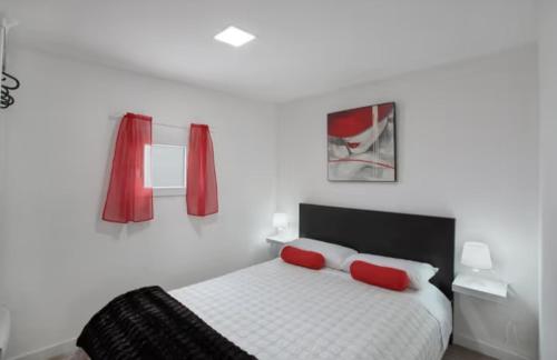 a bedroom with a bed with two red pillows at Villa Monica in Agüimes