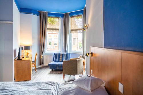 a bedroom with a bed and a chair and a window at Hotel Haus Martens in Hannover