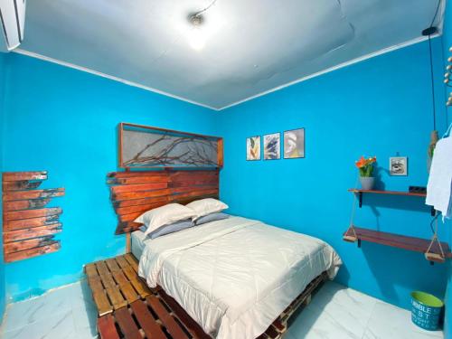 a blue bedroom with a bed with a wooden headboard at Evergreen Lodge in Padang