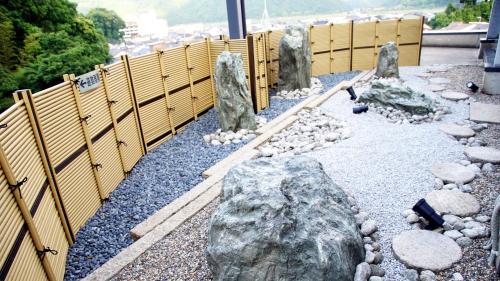 a garden with rocks and a wooden fence at Suizansou in Toyooka