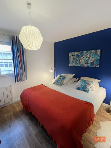 une chambre avec un grand lit avec un mur bleu dans l'établissement Le Sunset - Face mer, à Wimereux