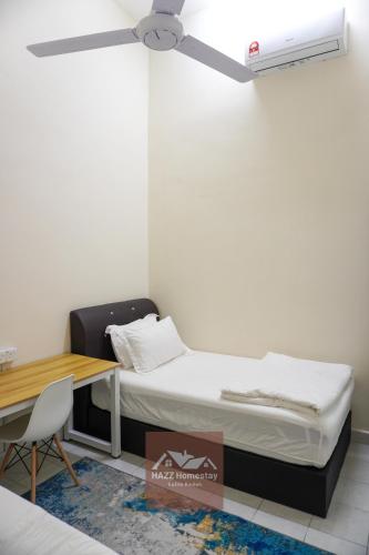 a room with a bed and a desk and a ceiling fan at HAZZ Homestay Kulim in Kulim