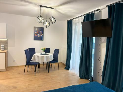 a dining room with a table and blue chairs at Wygodne Mieszkania Nova Mikołowska Apartamenty in Katowice