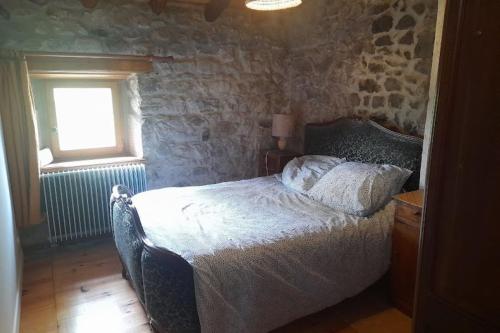a bedroom with a bed in a stone wall at La Maison de Pierre et Mizette in La Versanne