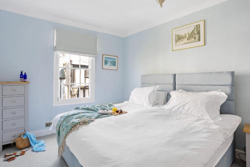 een slaapkamer met een bed met witte lakens en een raam bij Cherub Cottage located in the centre of Historic Dartmouth in Dartmouth