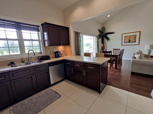 a kitchen with black cabinets and a living room at Colibri Court Antigua in Jolly Harbour