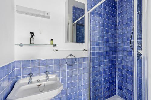 een blauw betegelde badkamer met een bad en een wastafel bij Cherub Cottage located in the centre of Historic Dartmouth in Dartmouth