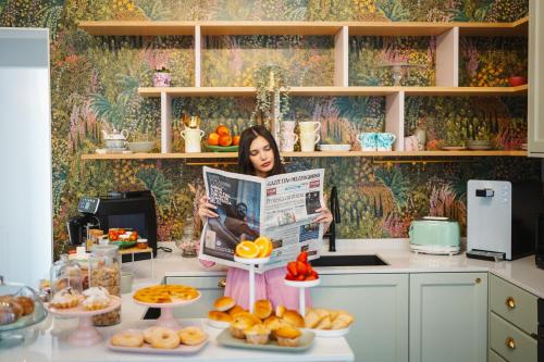 a woman is standing in a kitchen reading a newspaper at Casa Apuliae Bed & breakfast in Bitonto