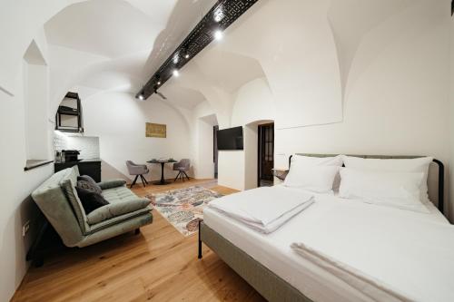 a bedroom with a large bed and a chair at Main Square Apartments & Rooms in Maribor