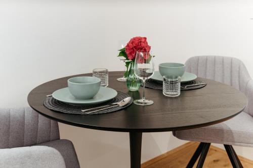 a dining room table with two chairs and a table with two cups and plates at Main Square Apartments & Rooms in Maribor