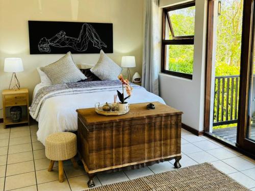 a bedroom with a bed and a table with a bowl on it at Bliss in the Bay Guesthouse in Plettenberg Bay