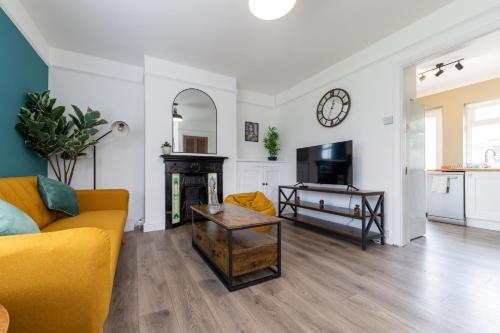 a living room with a yellow couch and a tv at Whole 3 Bedroom House - 2 Free Parking in St. Albans