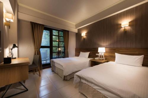 a hotel room with two beds and a desk at Ming Chi Resort in Datong