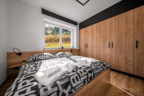 a bedroom with a black and white bed and a window at Apartmány BARTH Holiday - rezidence Krakonoš in Pec pod Sněžkou
