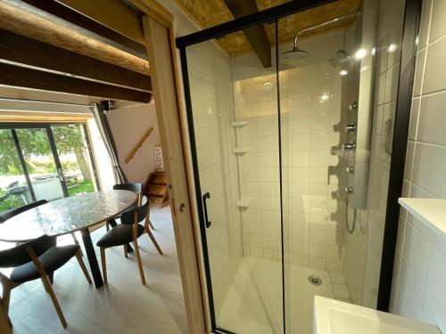 La salle de bains est pourvue d'une douche en verre, d'une table et de chaises. dans l'établissement L’oustal, à Nasbinals