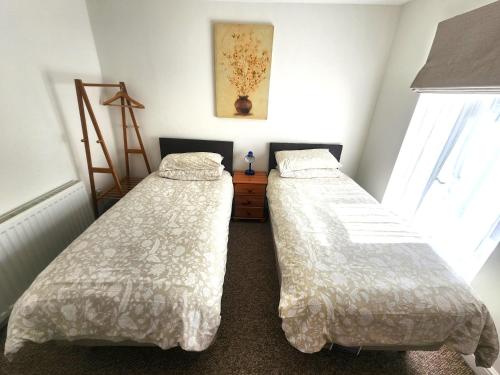 two beds sitting in a room with two windows at Bassett Flat with 2 Bedrooms and Superfast Wi-Fi in Sittingbourne