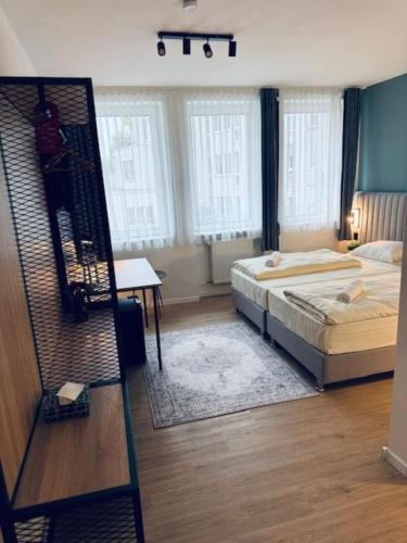 a bedroom with a bed and a desk and windows at Hotel Charlton in Hannover