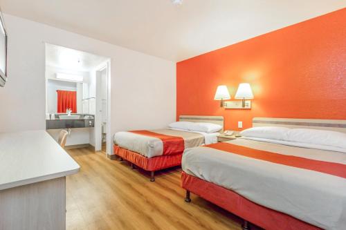 a hotel room with two beds and an orange wall at Motel 6-Phoenix, AZ - West in Phoenix