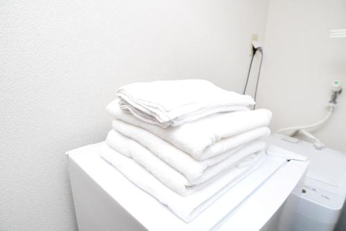 una pila de toallas blancas sentadas en un estante en ACT Residence No.1, en Tokio