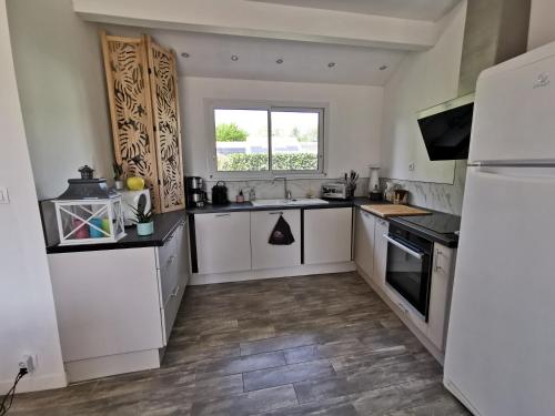 une grande cuisine avec des armoires blanches et une fenêtre dans l'établissement MAISON T4 style ARCACHONNAISE, à Gujan-Mestras