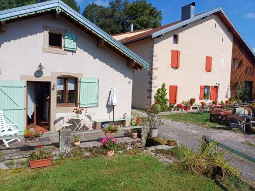 Maison blanche avec volets orange et vert dans l'établissement Gîte du Ruisseau d'Argent, à Archettes