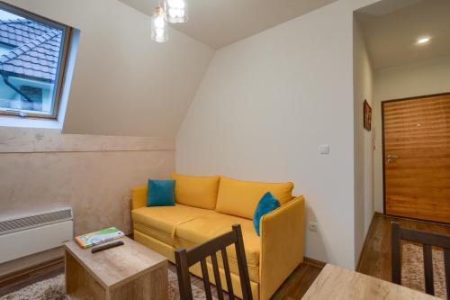 a living room with a yellow couch and a table at All Seasons Residence in Zlatibor