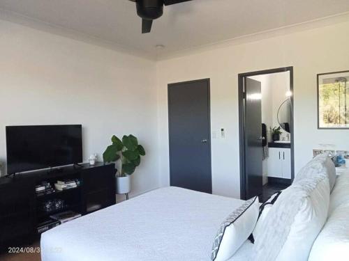 a bedroom with a bed and a flat screen tv at Cairns Chic Suite - Motel Room A in Woree