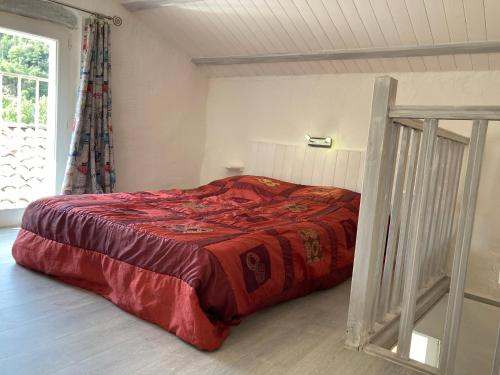 a bedroom with a bed with a red comforter at Maison bord de rivière in Roquestéron