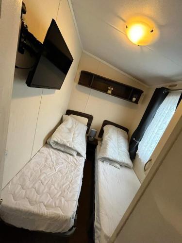 a small room with two beds and a tv at 163 Holiday Resort Unity Brean sands Pet friendly in Berrow