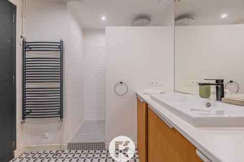 une salle de bain blanche avec une douche et un lavabo dans l'établissement R'Apparts T3 Paris 9ème L'Incontournable, à Paris